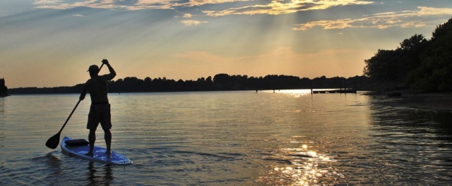 practicando sup con un atardecer de fondo